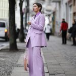 Девушка в лиловом костюме стоит на улице